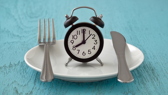 A white plate with a fork, knife and an alarm clock © colourbox 