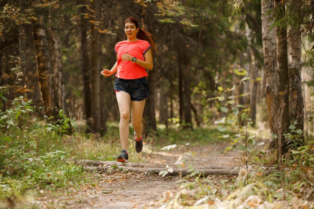 Woman in short sportswear running through the forest