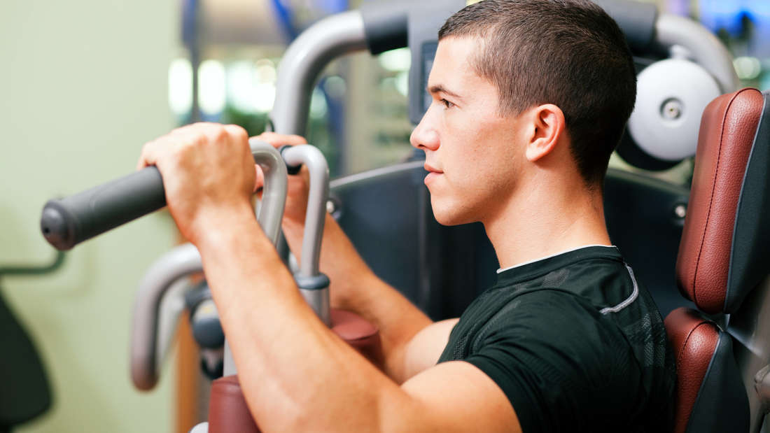 Muscular young man doing a fitness exercise in the Butterlfy machine