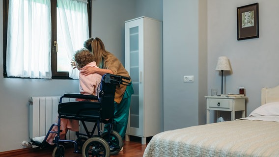 A nurse looks out the window with an old woman sitting in a wheelchair.  © Colourbox Photo: 81162