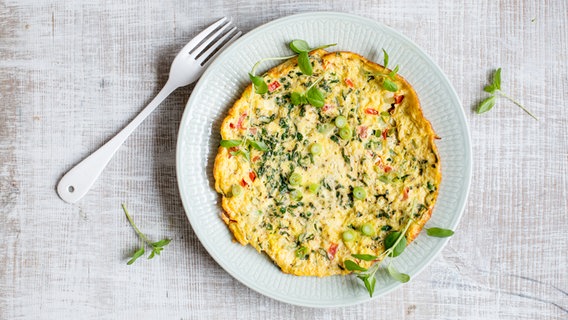 A plate of tomato and zucchini scrambled eggs stands on a table.  © NDR Photo: Claudia Timmann